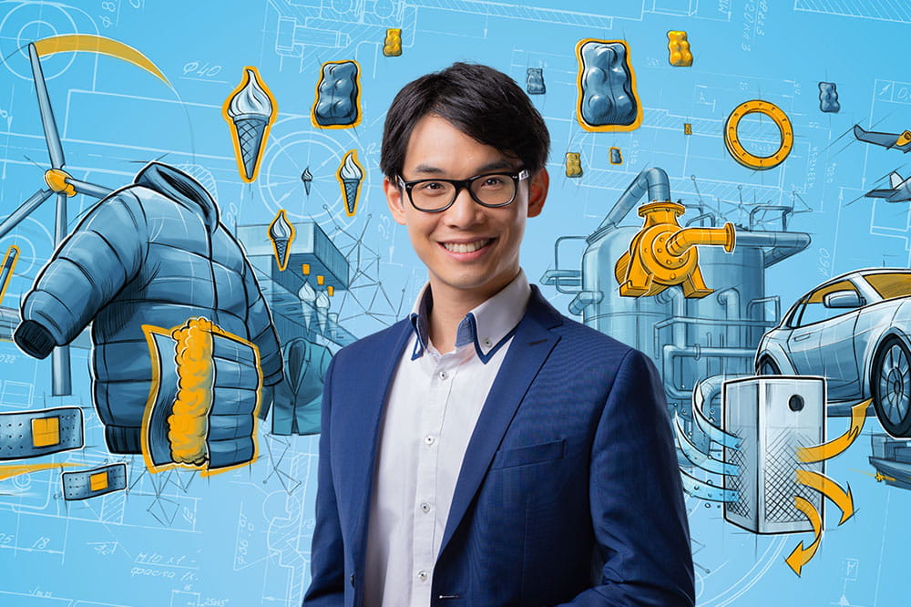 Young man in suit and glasses in front of illustrations of Freudenberg Sealing Technologies' market segments, such as a car or a wind turbine.