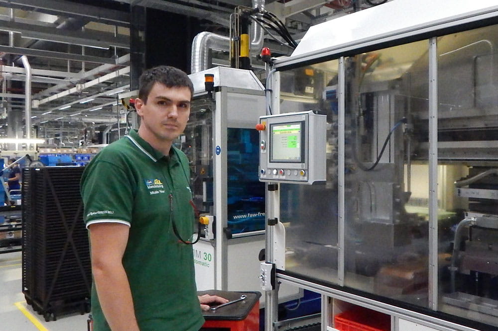 Half close up shows Peter Mikulas standing in front of a machine