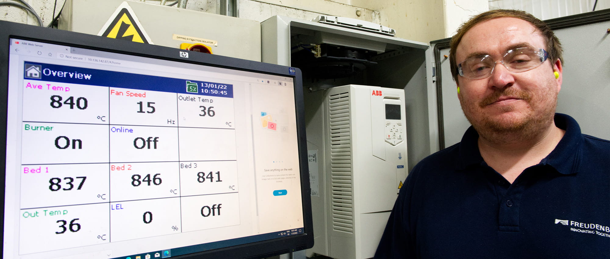 A man is standing in front of a monitor.