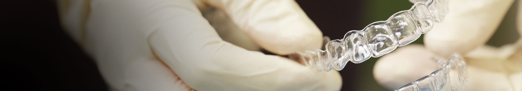 Close-up of a doctor's gloved hands holding a silicone mouthguard for dental care