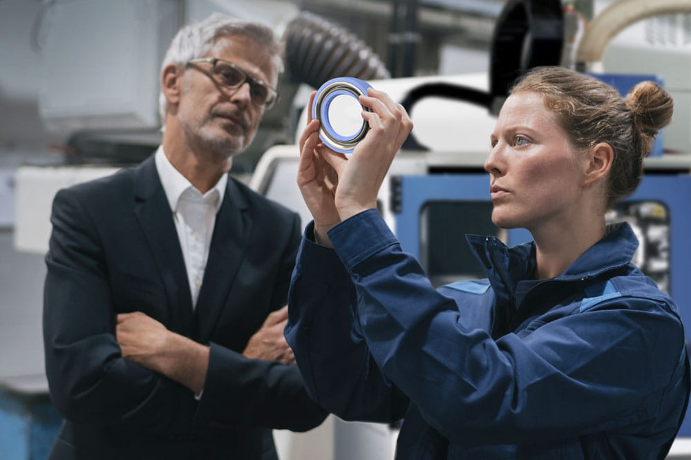 Man and woman standing in front of a turning machine looking at a blue seal together