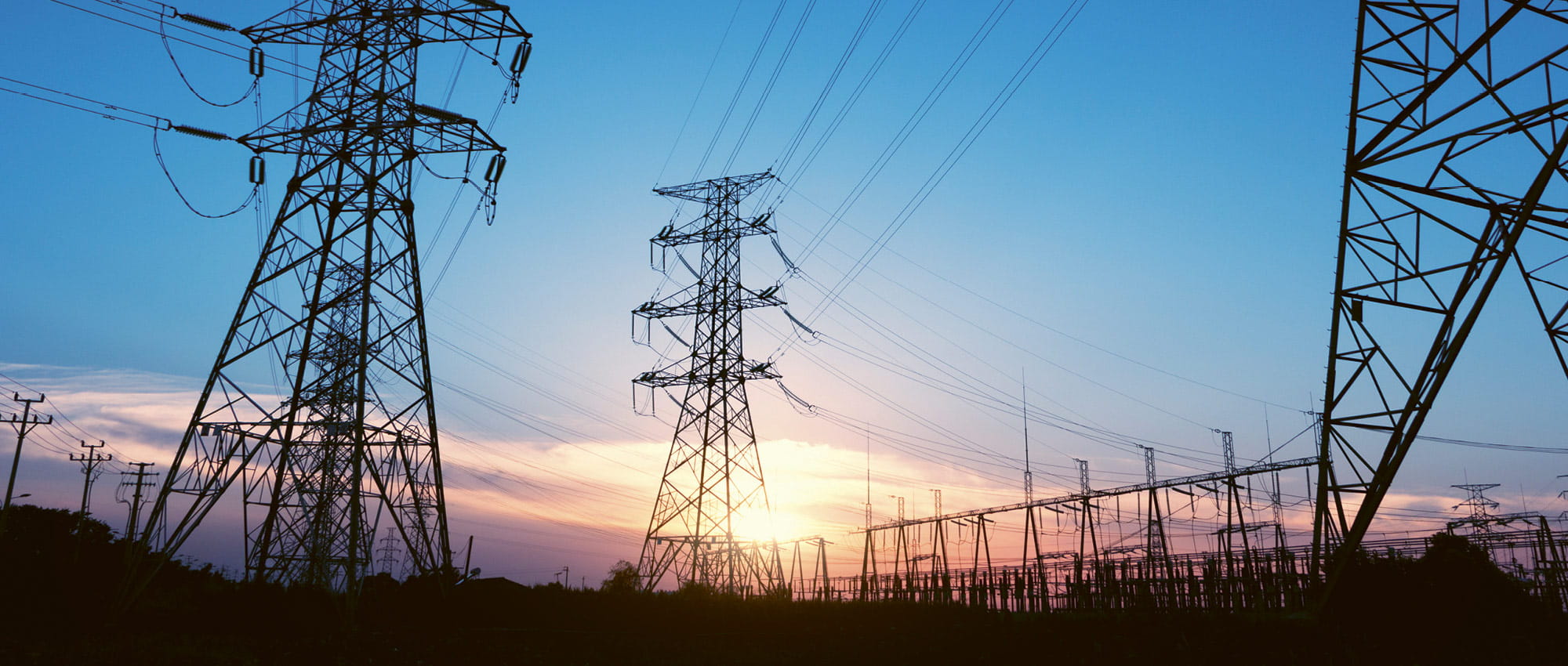 Electricity pylons in front of a sun set.