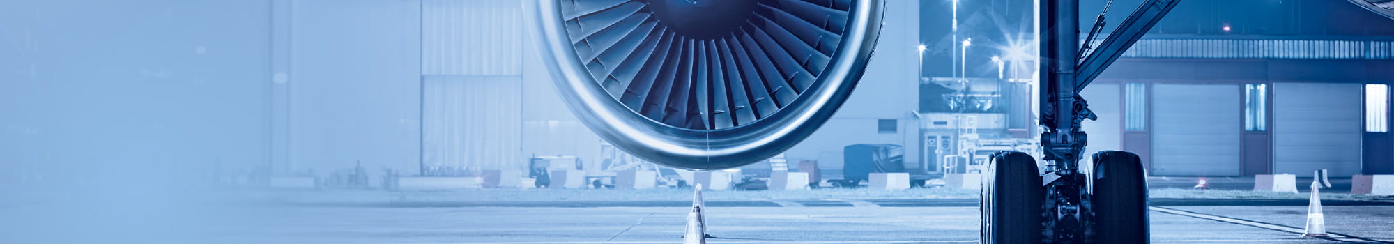 Turbine of an airplane is in focus and in the background is an airfield