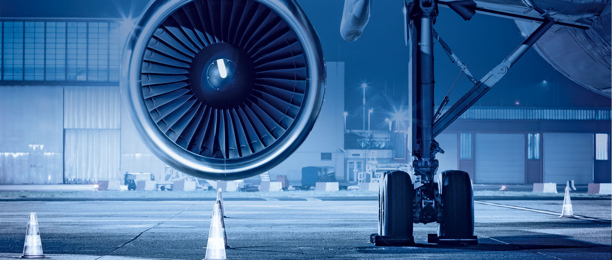 Turbine of an airplane is in focus and in the background is an airfield