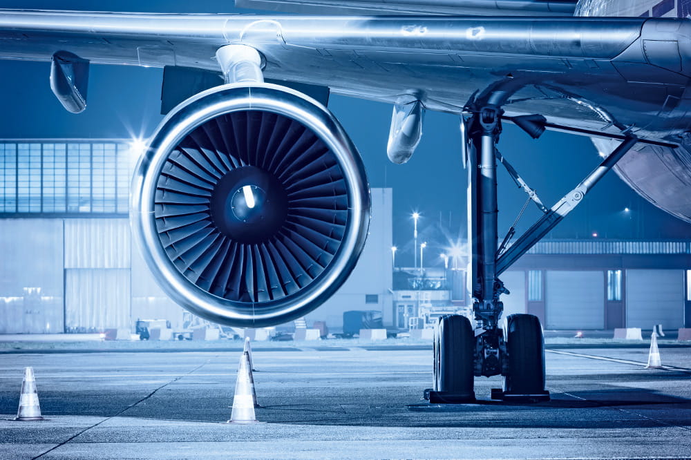Turbine of an airplane is in focus and in the background is an airfield