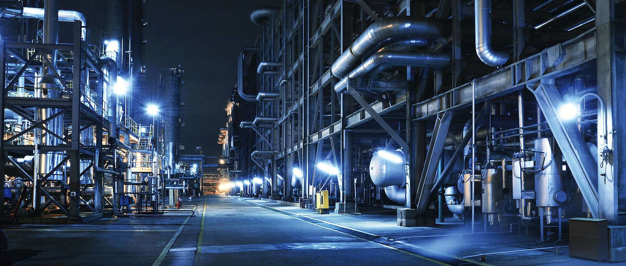 Chemical plant at night with several pipes in blue color scheme.