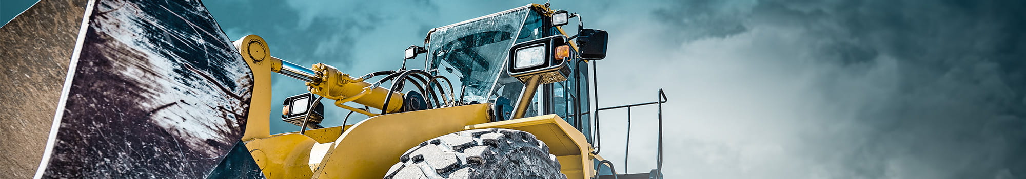 Front loader construction machine in front of cloudy sky