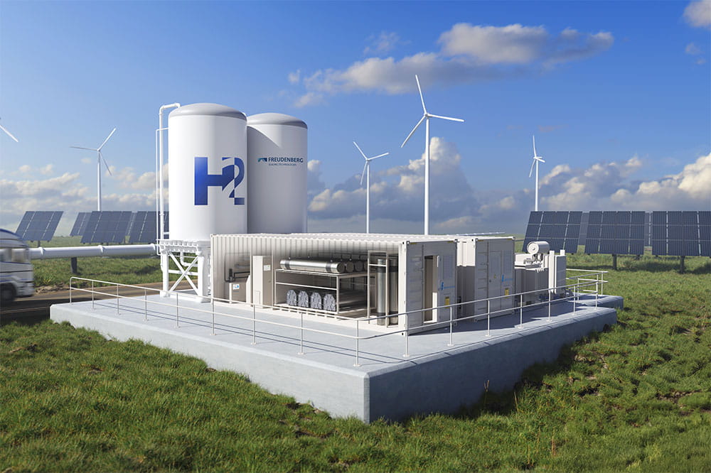 A hydrogen production facility with storage tanks, wind turbines, solar panels, and a truck in a grassy landscape under a partly cloudy sky.