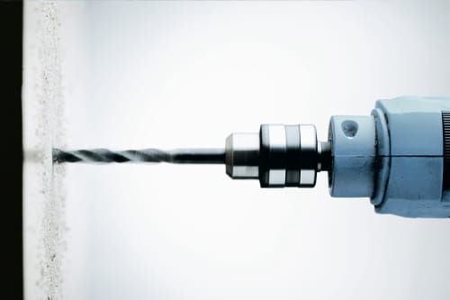 Close up of a drill head drilling a hole in the wall