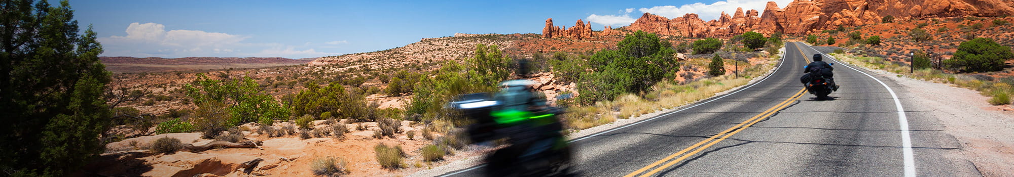 Two motorcyclists on a barren country road in the desert 