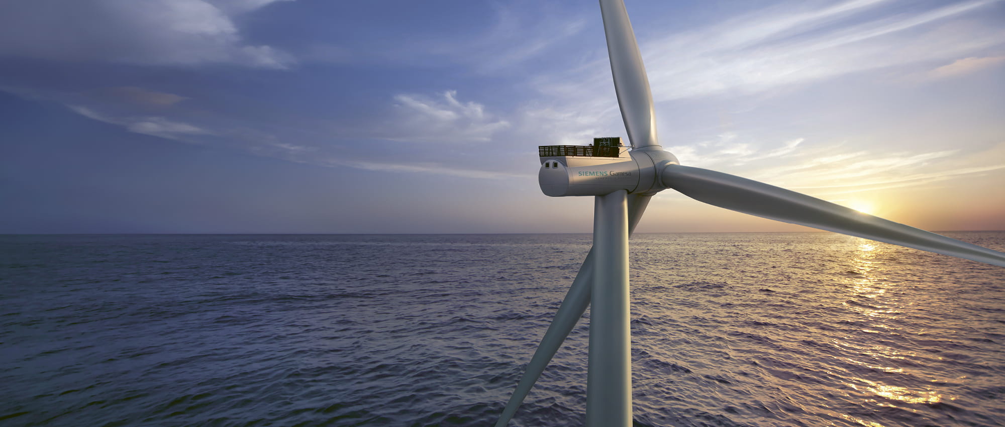 Offshore windmill in front of the sea and a sunset.