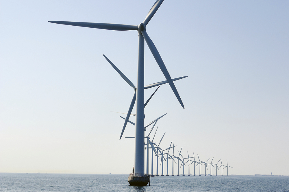 A row of windmills standing in the middle of the sea.
