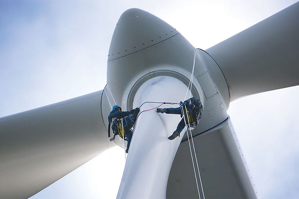 Two installers climb up a wind turbine.