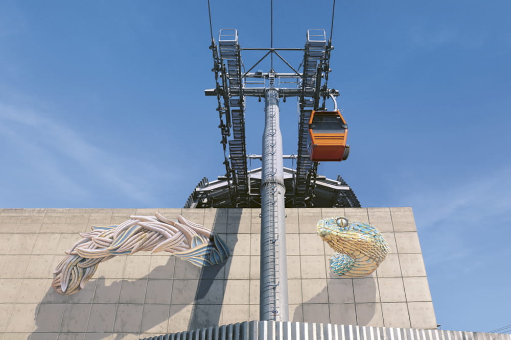 Aerial tram in front of a wall with a work of art of a snake.