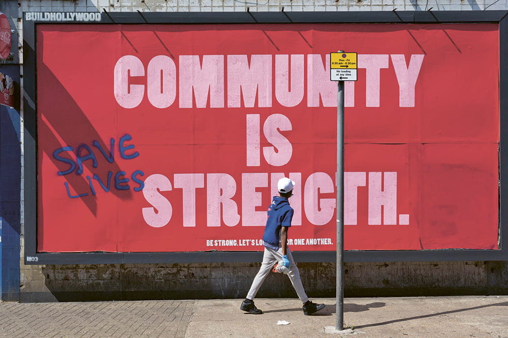 A boy in front of a large red poster that reads Community is strength.