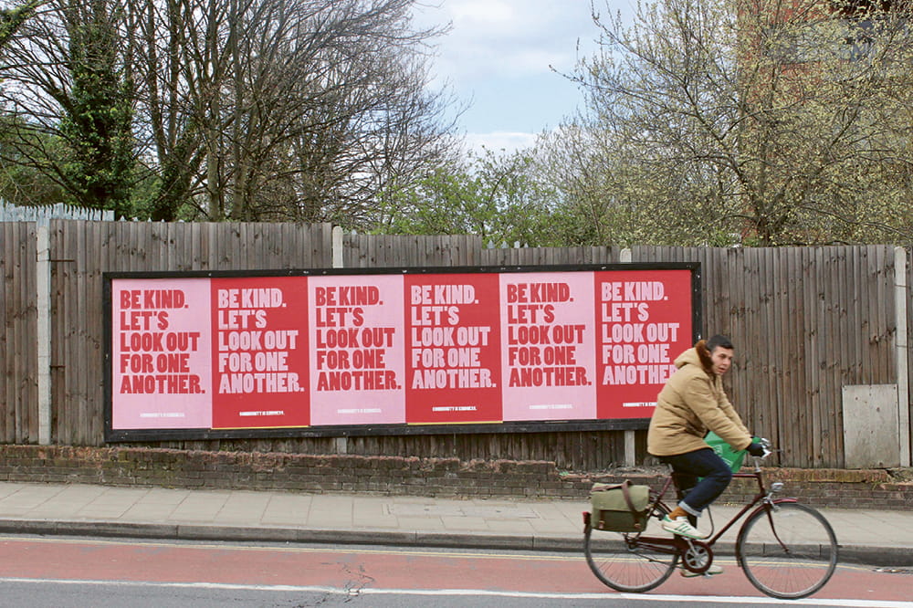A bicyclist rides past a row of red posters that read 