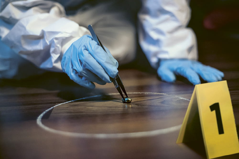 Gloved hand grasps an evidence with tweezers