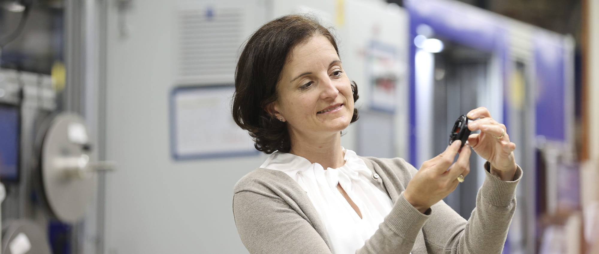 Tanja Heislitz, Technical Director E-Mobility at Freudenberg Sealing Technologies, holds a DIAvent plastic part in her hands and looks at it.