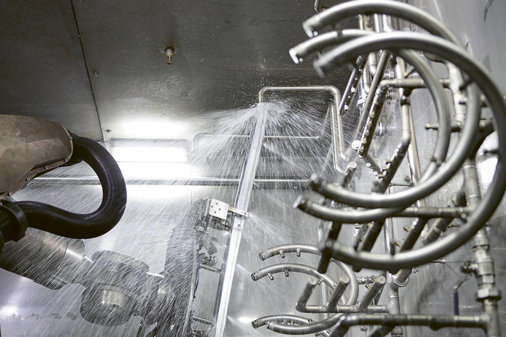 Robot being sprayed with water in a washing plant. Copyright by KUKA Group