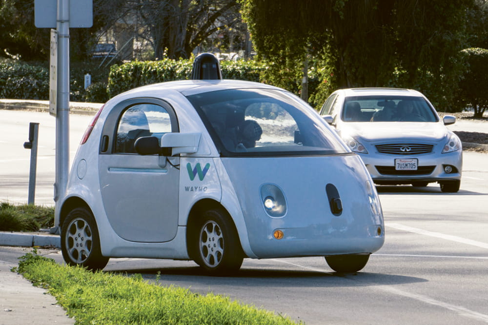 Blue autonomous car turning onto a street with a moving car