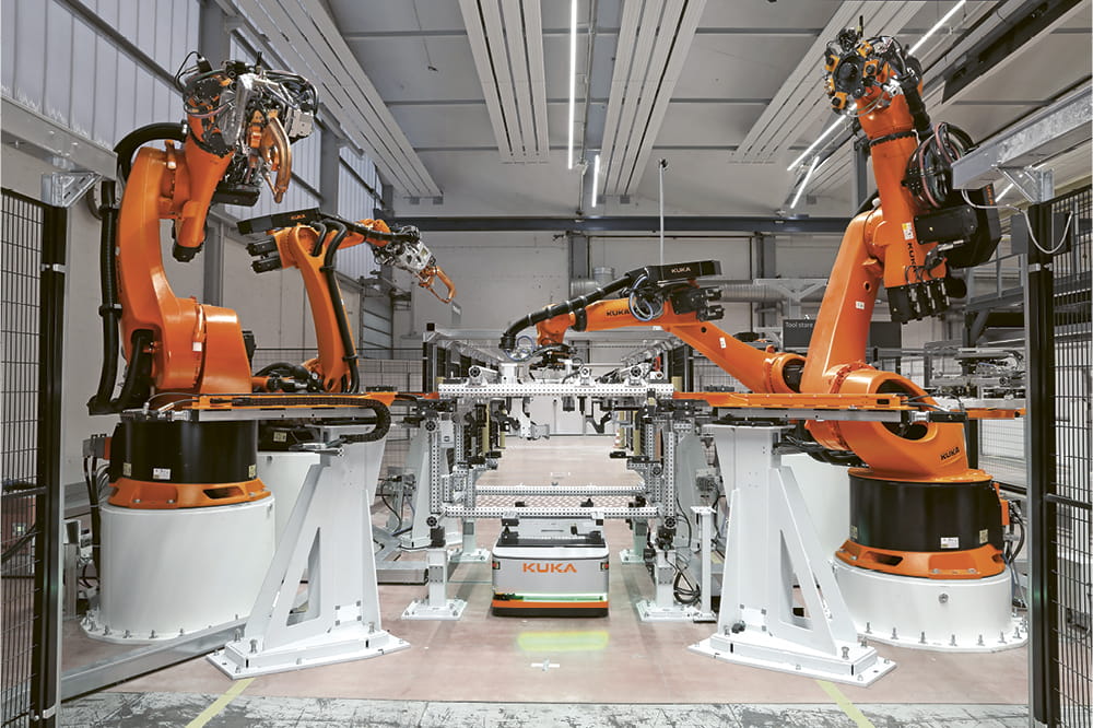 Orange robot arms working in a row in a factory