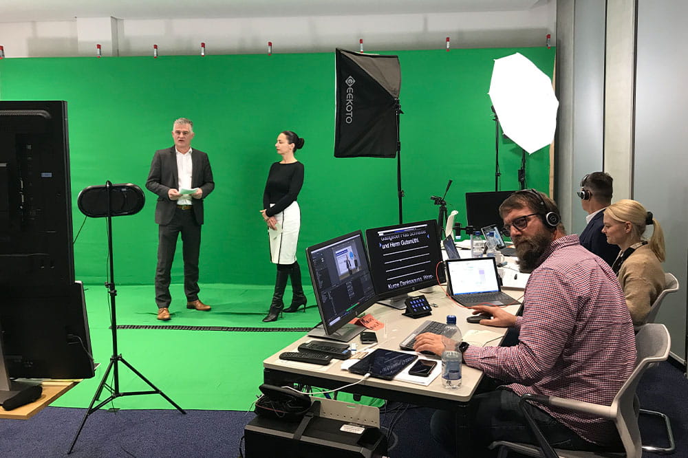 Making of the Digitaler Pharma Dialog. Two people in front of a green screen and three people on the right side editing the scene