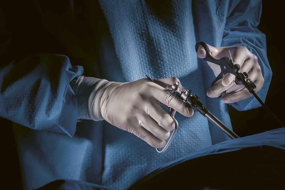 Close-up of two hands in gloves holding surgical tools.