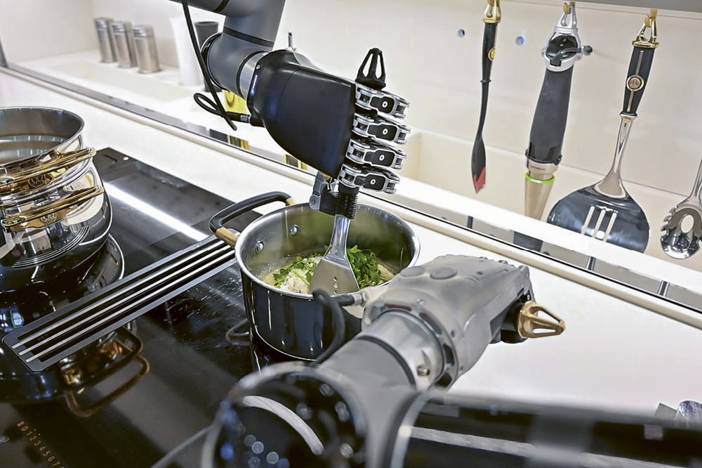 Robotic arms on the stove preparing food in a pot.