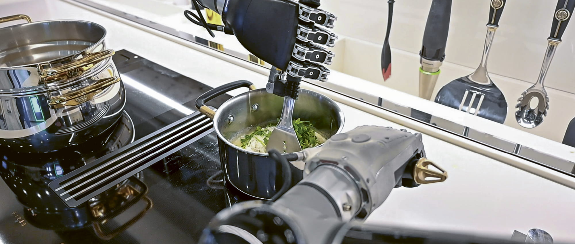 Robotic arms on the stove preparing food in a pot.