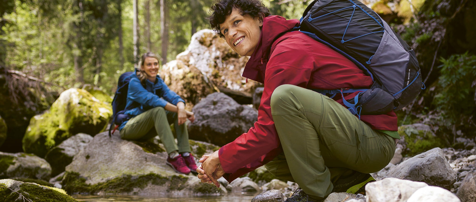 A man and a women are sitting smilingly at a creek. Copyright: VAUDE: M. Attenberger