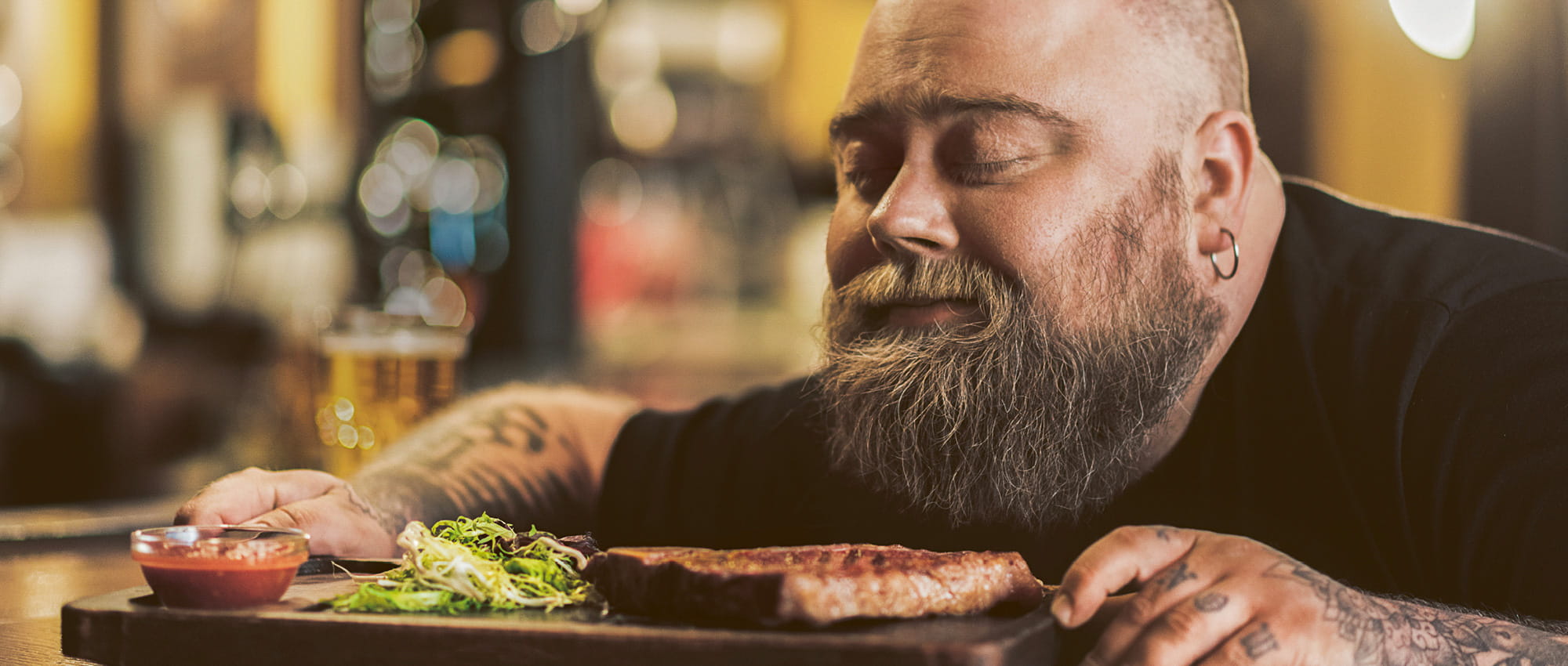 A bearded man smells a plate of food with his eyes closed. Copyright: iStock: YakobchukOlena 