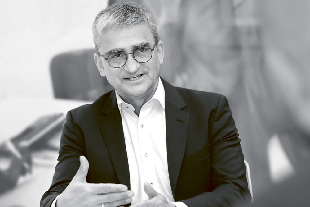 Black and white portrait of a man with glasses who is talking.