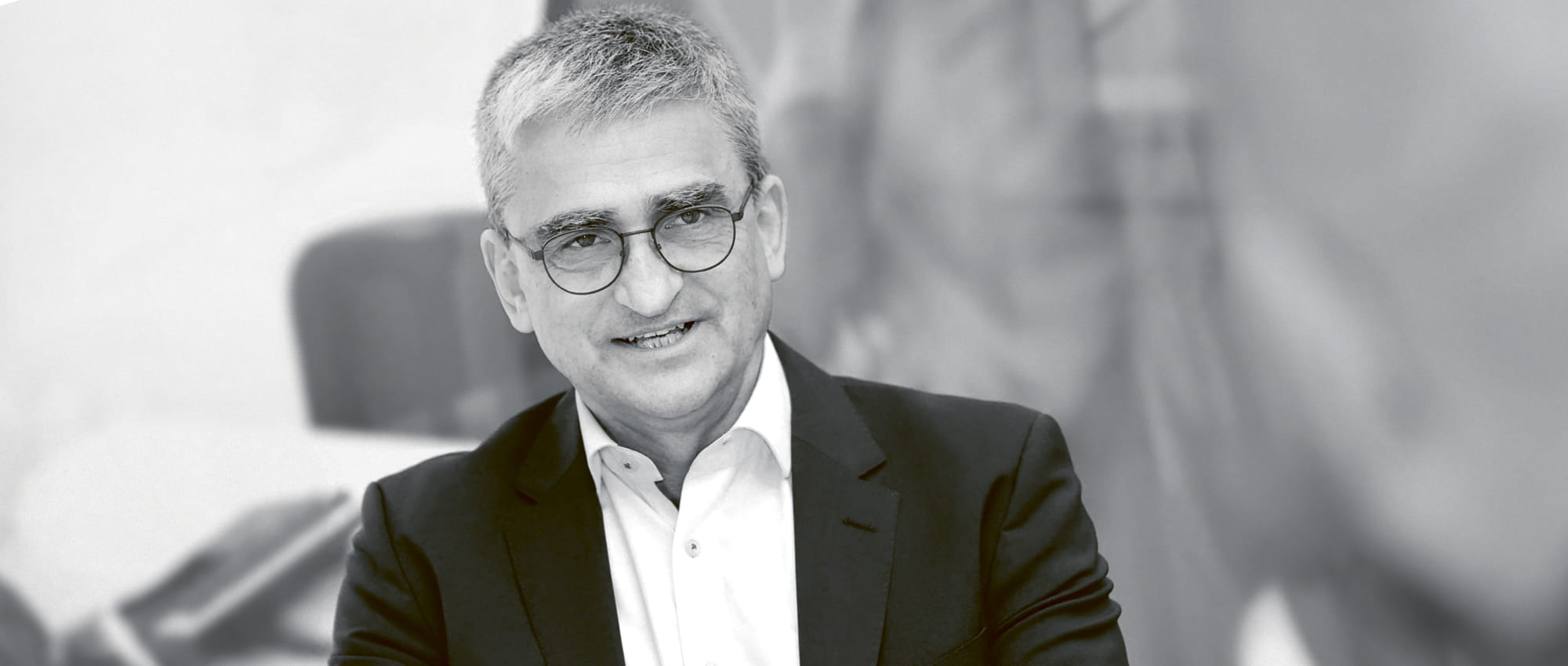 Black and white portrait of a man with glasses who is talking.