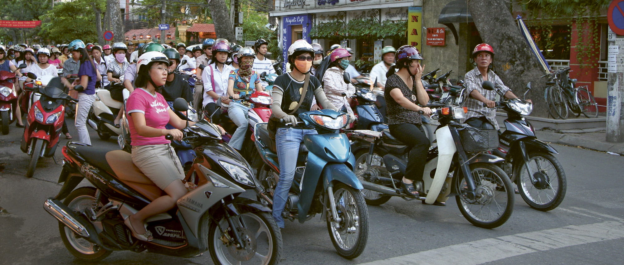 A crowd of motorcyclists are waiting at an intersection.