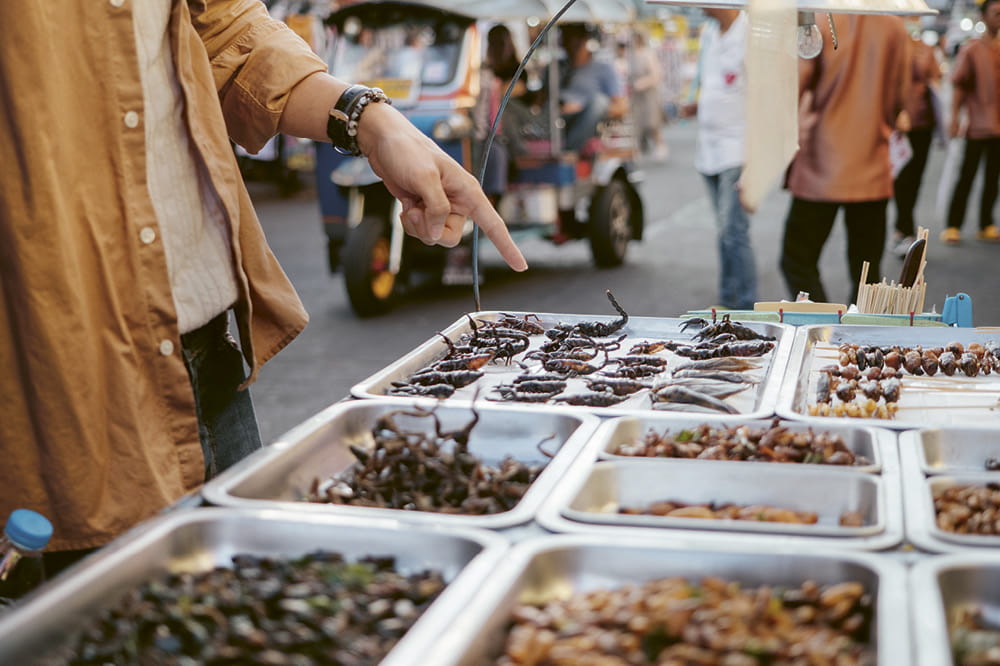 A man at a market points a finger at insects on display. Copyright: iStock/staticnak1983