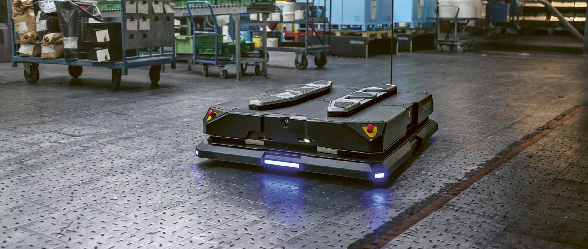 A black square robot GoPal travels through a warehouse