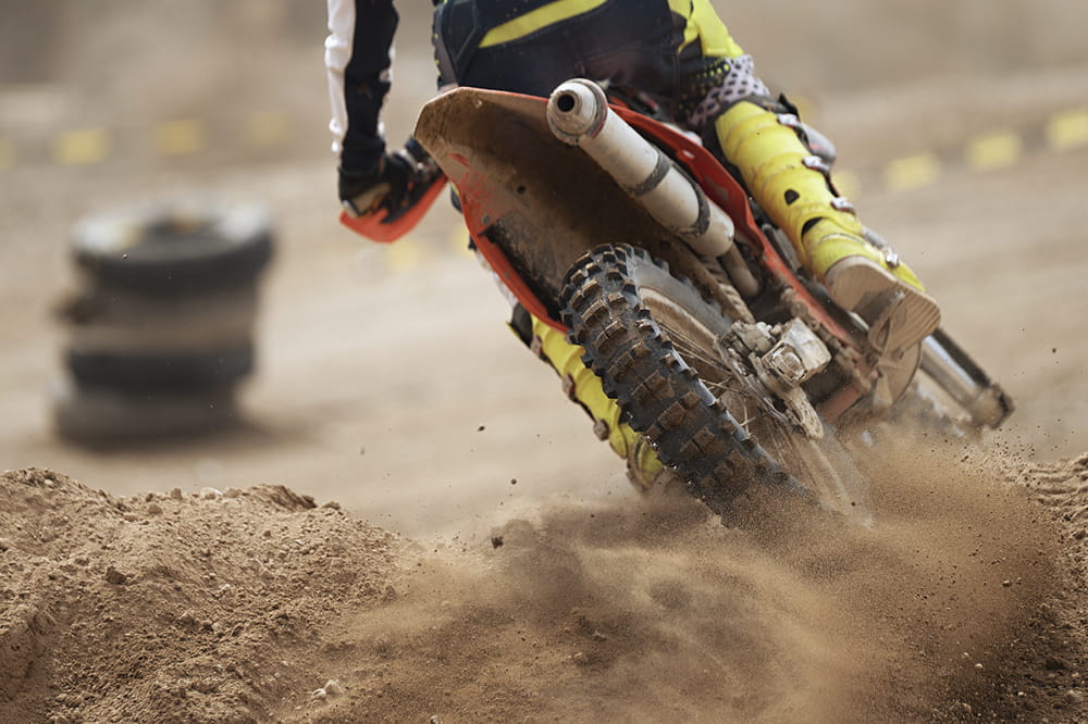 A motocross bike rides over sand. 