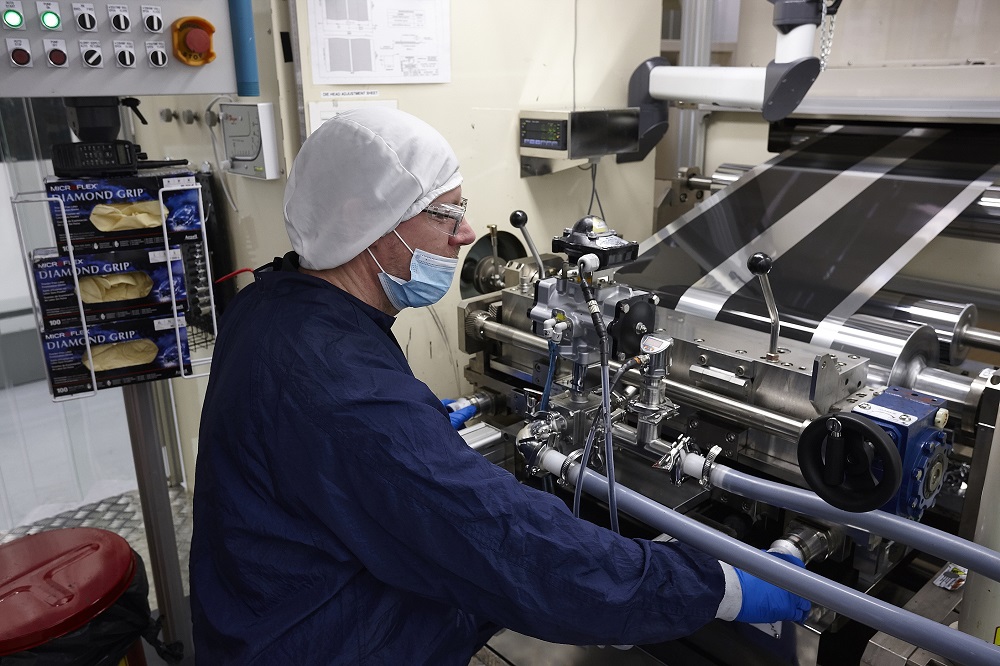 an XALT Energy employee in protective gear at a battery cathode production line