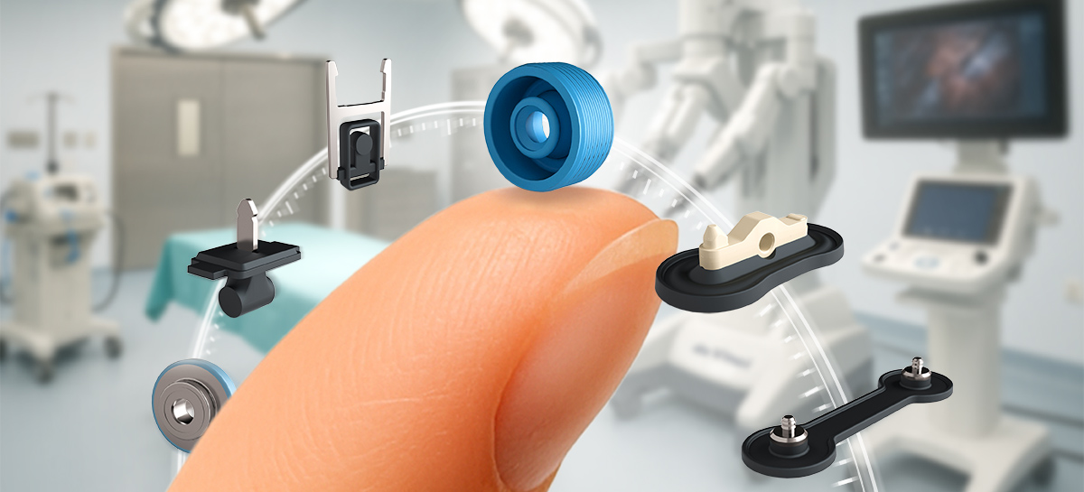 A close-up of a fingertip balancing several small micro seals, with a blurred surgical room in the background.