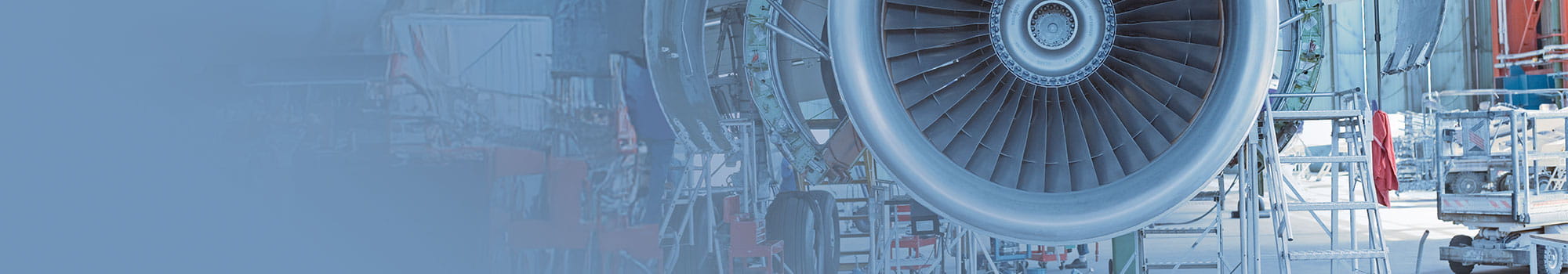 Close-up of a jet engine under maintenance in a hangar, showcasing the turbine and surrounding scaffolding.