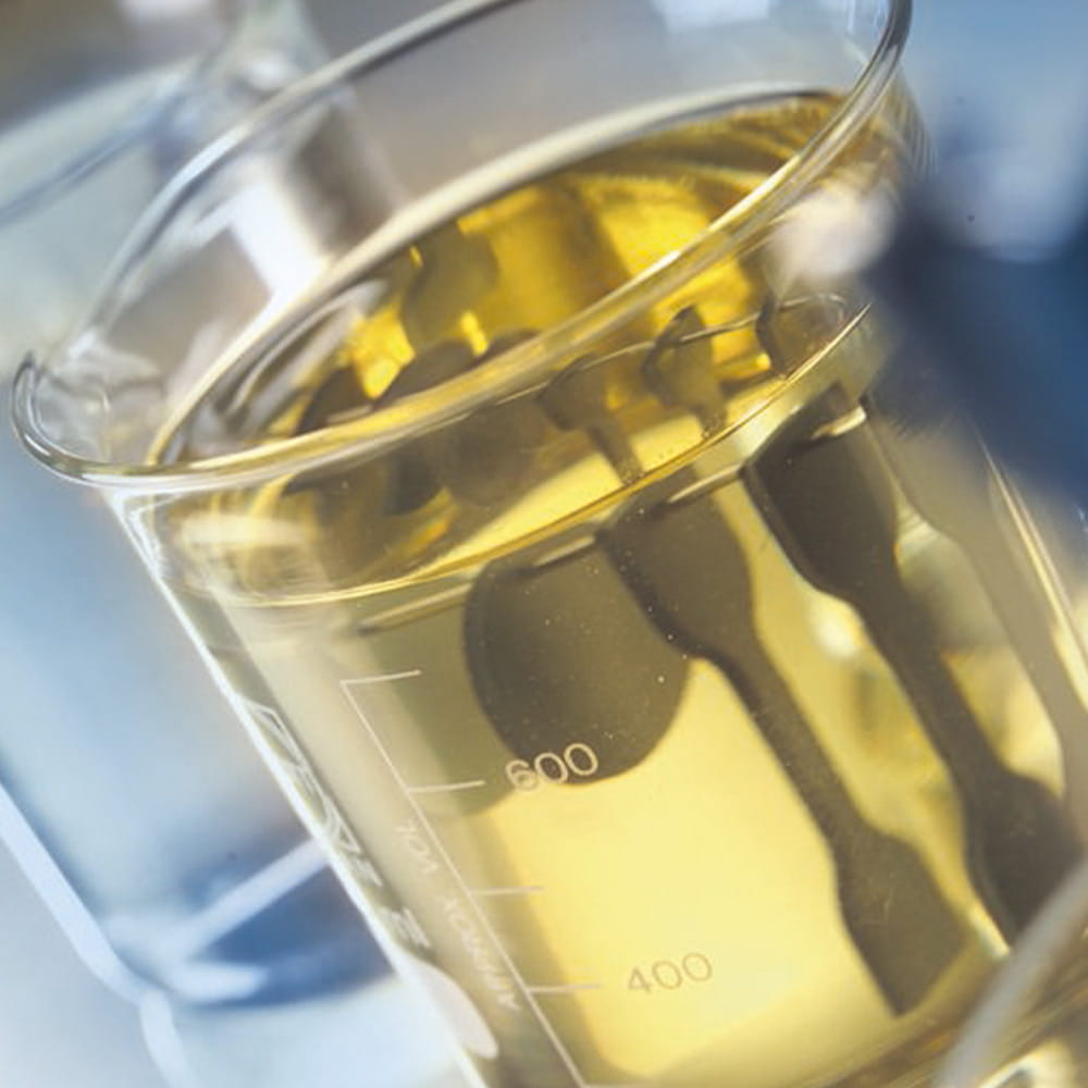 Close up of chemical measuring cup with yellow lubricating oil