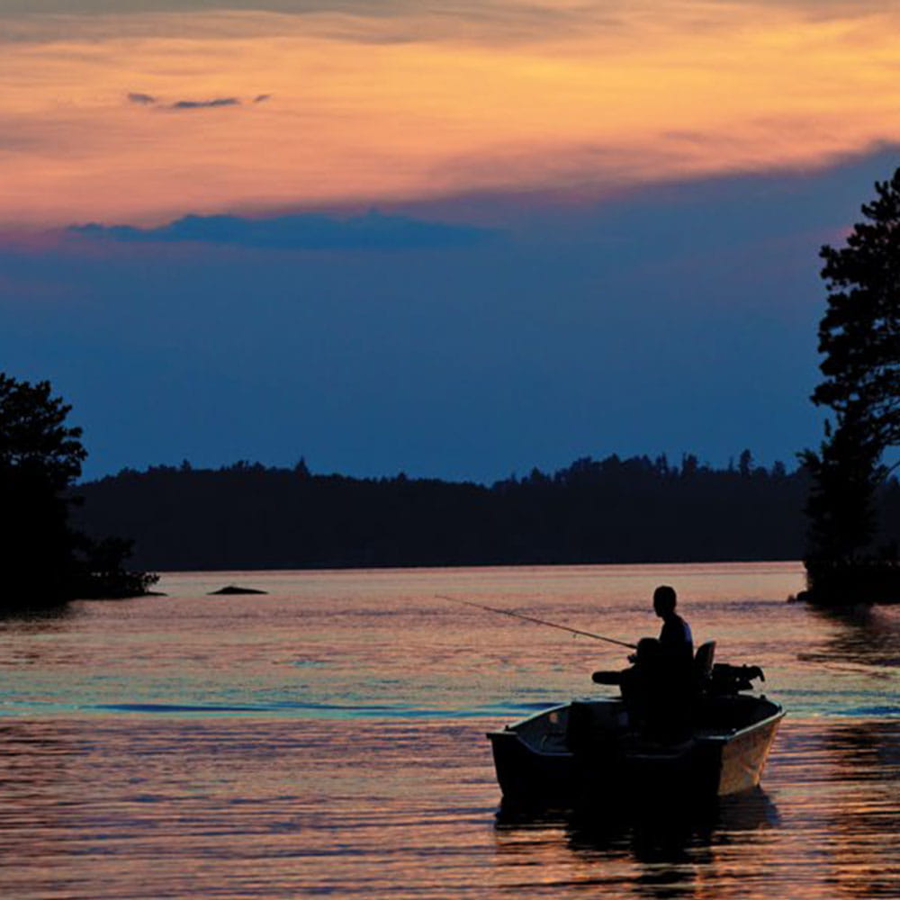 Fisherman fishing in a lake from his boat during twilight  