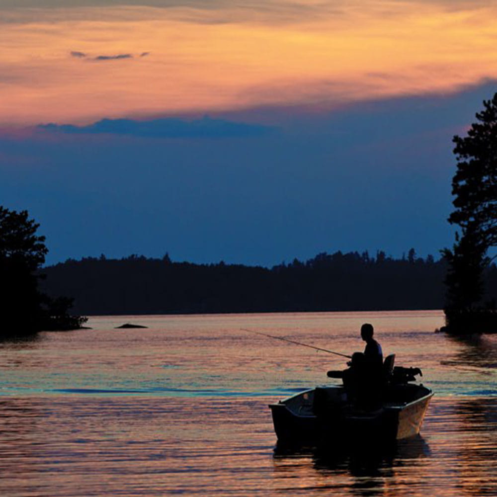 Fisherman fishing in a lake from his boat during twilight