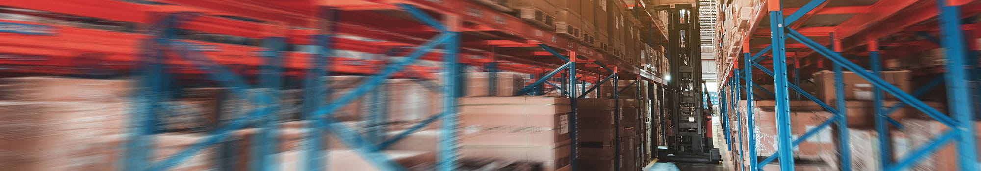 Forklift truck moves a package through a row of racks with stored boxes in a warehouse