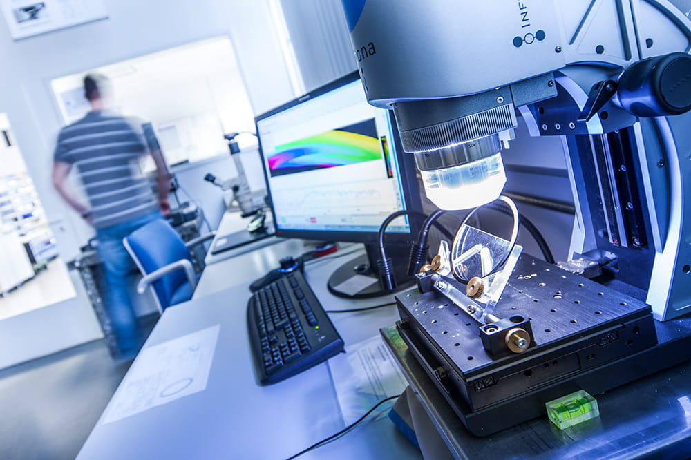 Seal under microscope in quality office with computer and employee from behind