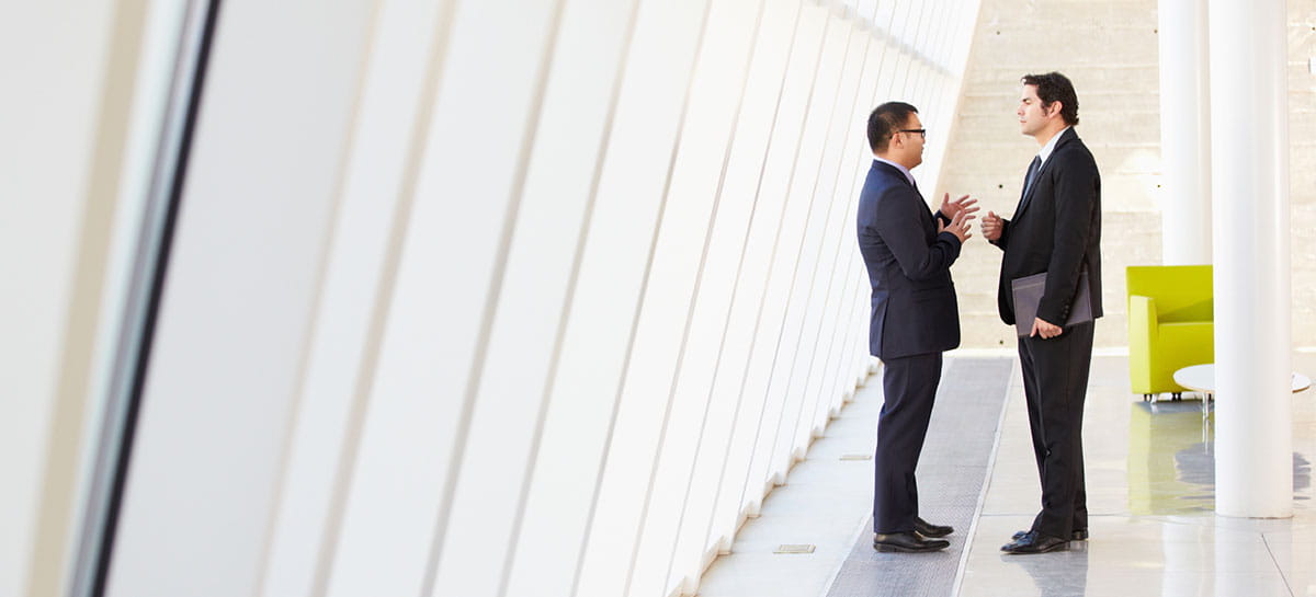 Two men in suit are talking in a room with slanted roof windows