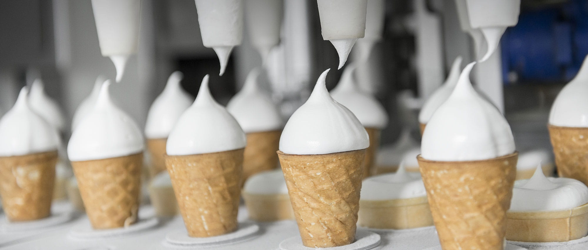 Eistüten sind in einer Vorrichtung und mit Spritzgerät wird die Eiscreme auf die Eistüte gesetzt