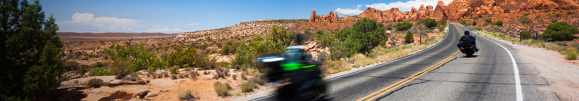 Zwei Motorradfahrer auf einer kargen Landstraße in der Wüste 