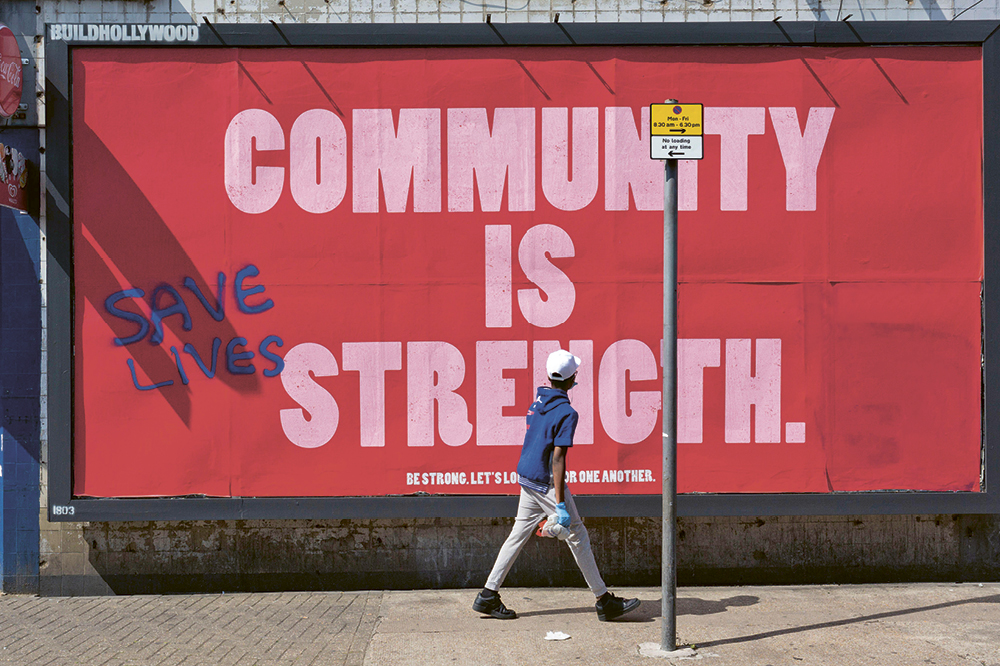 Ein Junge vor einem großen roten Plakat mit der Aufschrift Community is strength.