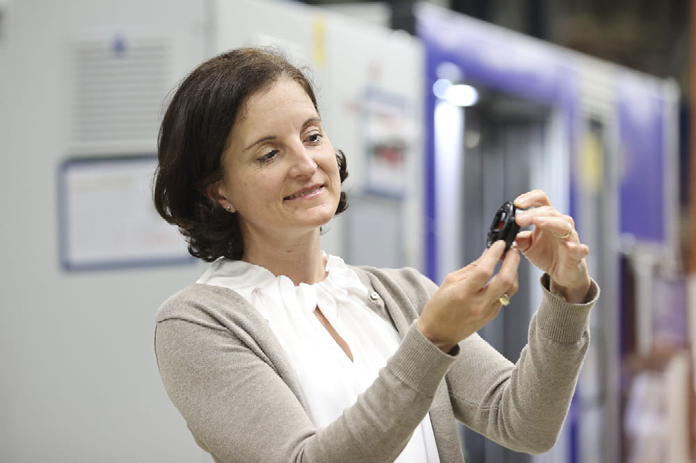 Tanja Heislitz, Technical Director e-mobility bei Freudenberg Sealing Technologies, hält ein Kunststoffteil DIAvent in den Händen und betrachtet es.